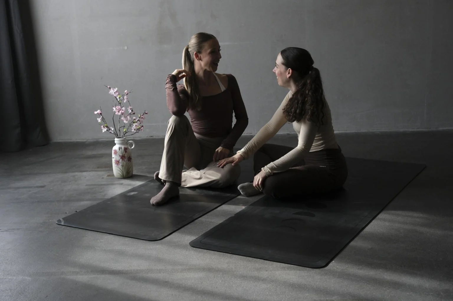 Selina und Amaya sitzen bei SELAYA gemeinsam auf Pilatesmatten.
